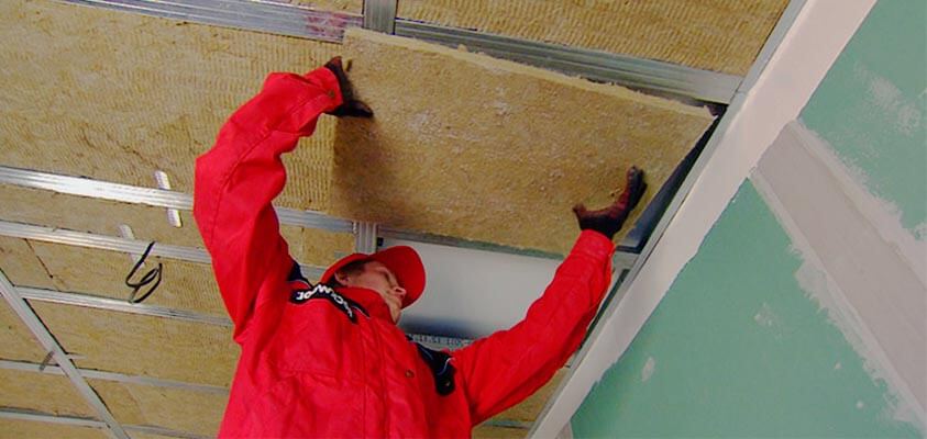 Укладка звукопоглощающего материала на каркас при монтаже звукоизоляции под натяжной потолок